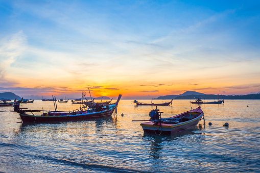 scenic sunrise above fishing boats in Rawai seasmall fishing boat on Rawai beach